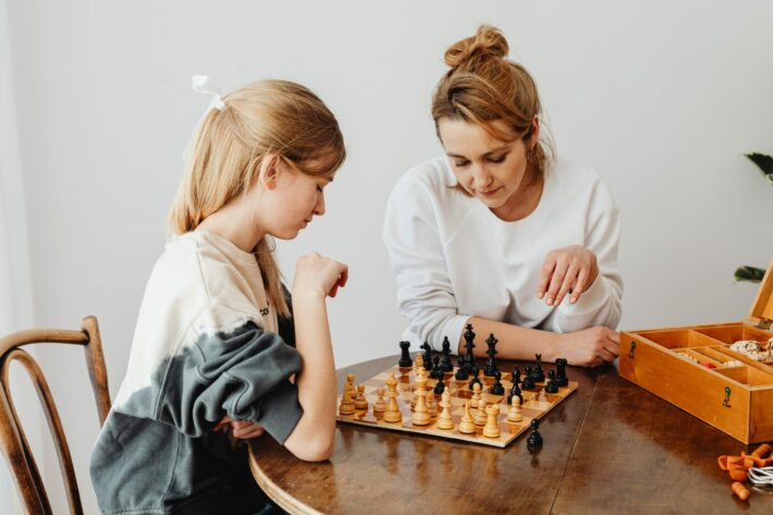 What are the age-related factors that influence the attainment of grandmaster or master titles in chess